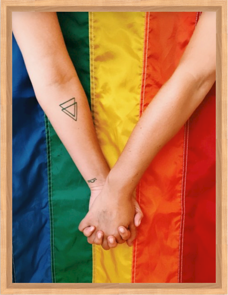 Couple holding hands in front of pride flag