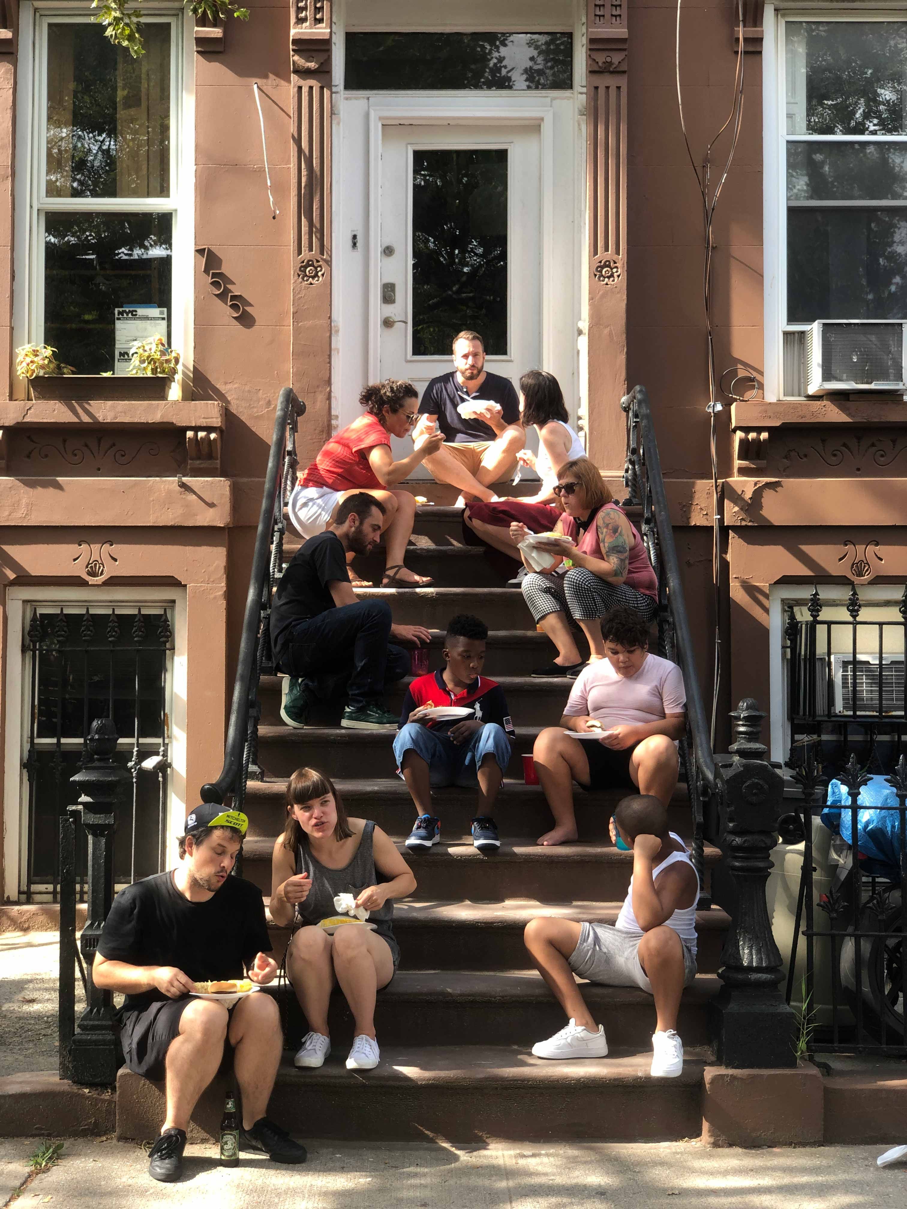 People eating on a Brooklyn stoop in a gold frame