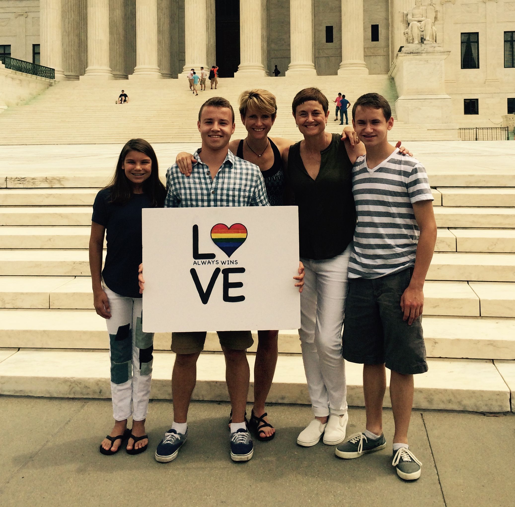 Family with pride sign in front of Supreme Court