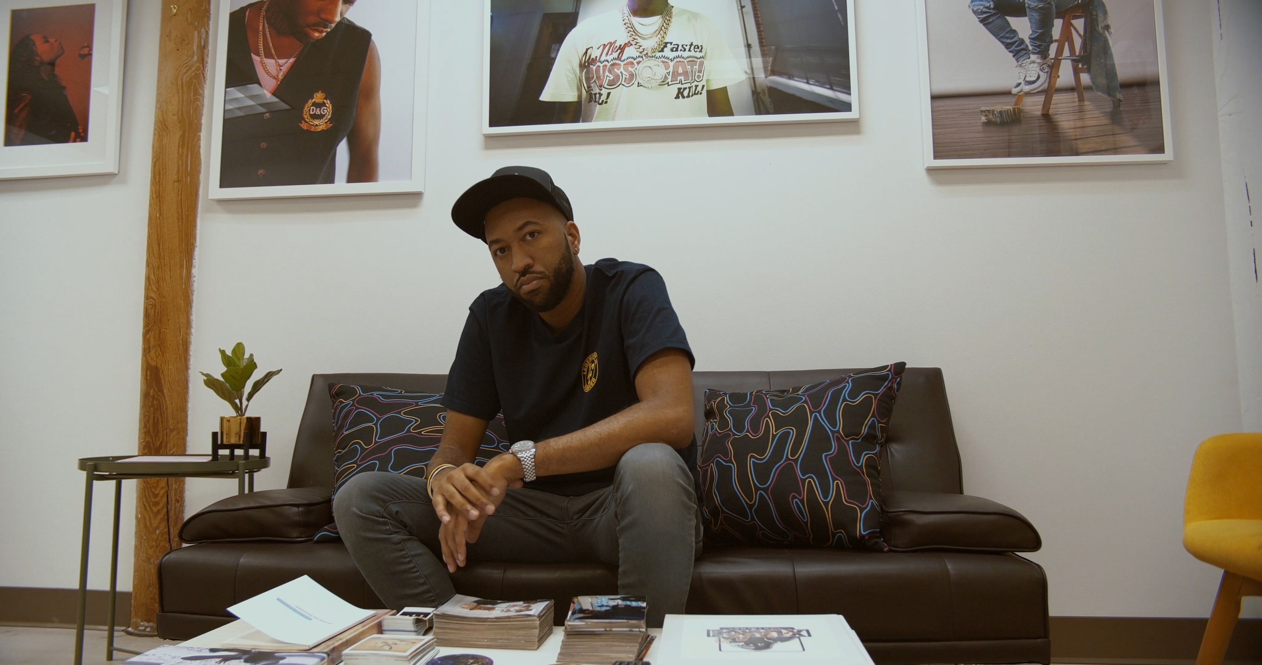Cam Kirk sitting on coach with framed photos above